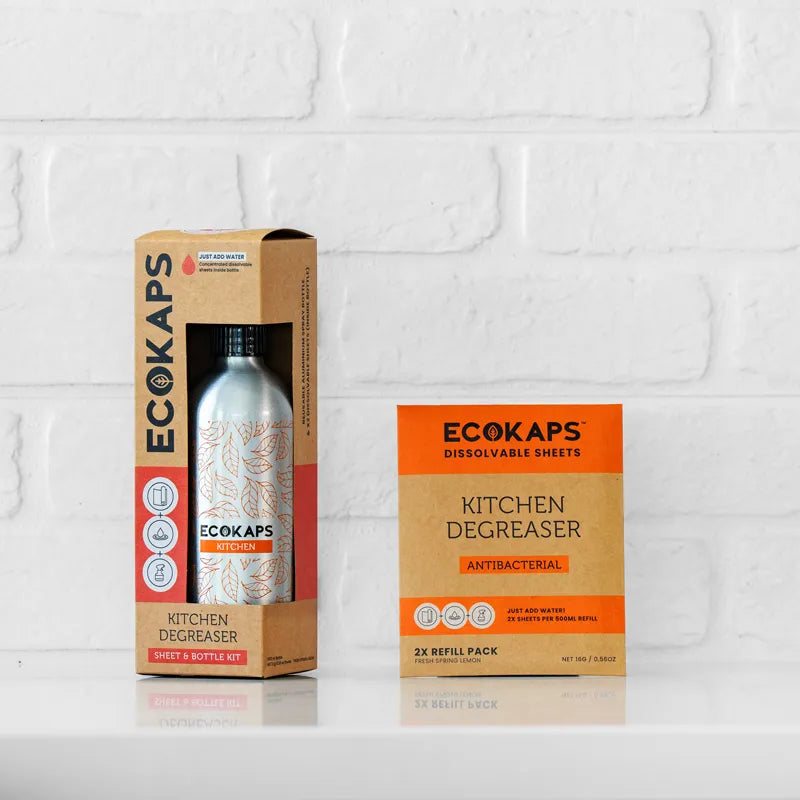 ECOKAPS kitchen degreaser sheet & bottle kit and refill envelope on a white brick wall background