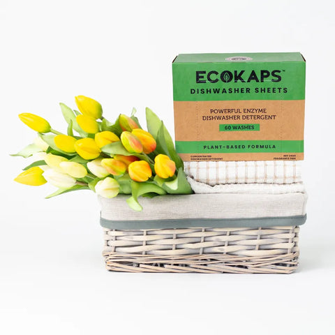 ECOKAPS Dishwasher Enzyme Plant based sheets, sitting on towels in a basket with flowers